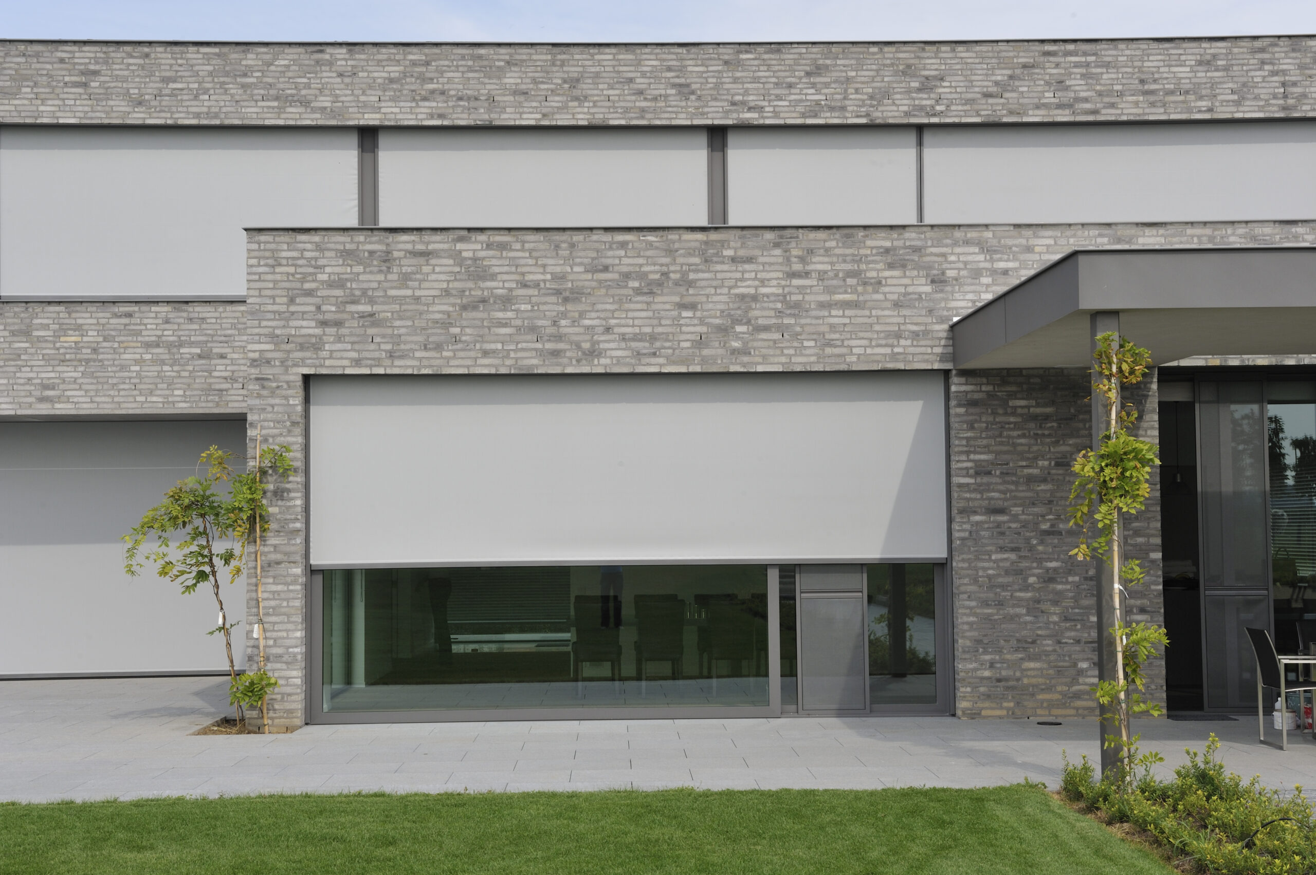 Modern building with a grey external fabric screens partially covering a large ground-floor window.