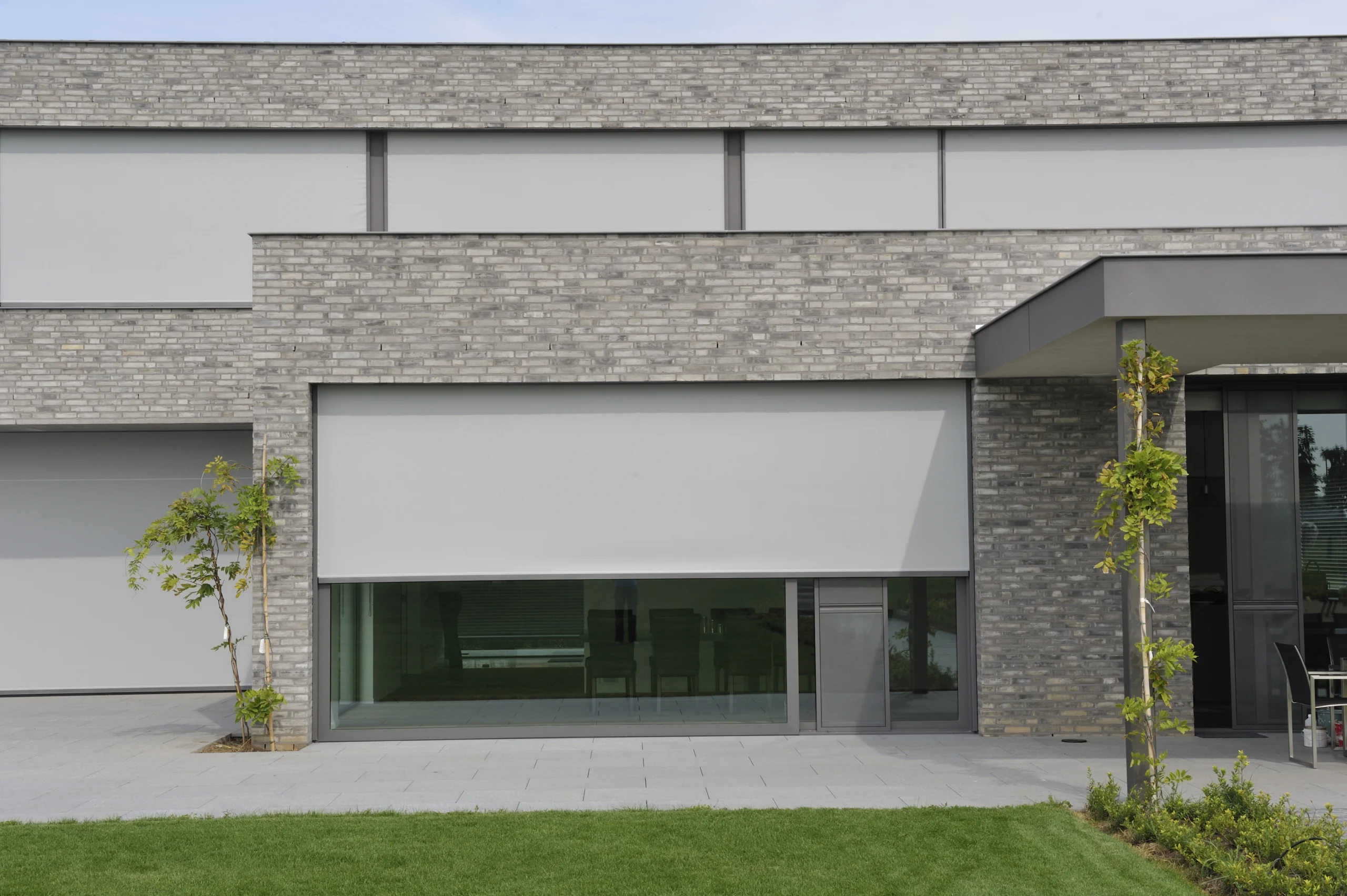 Modern building with a grey external fabric screens partially covering a large ground-floor window.