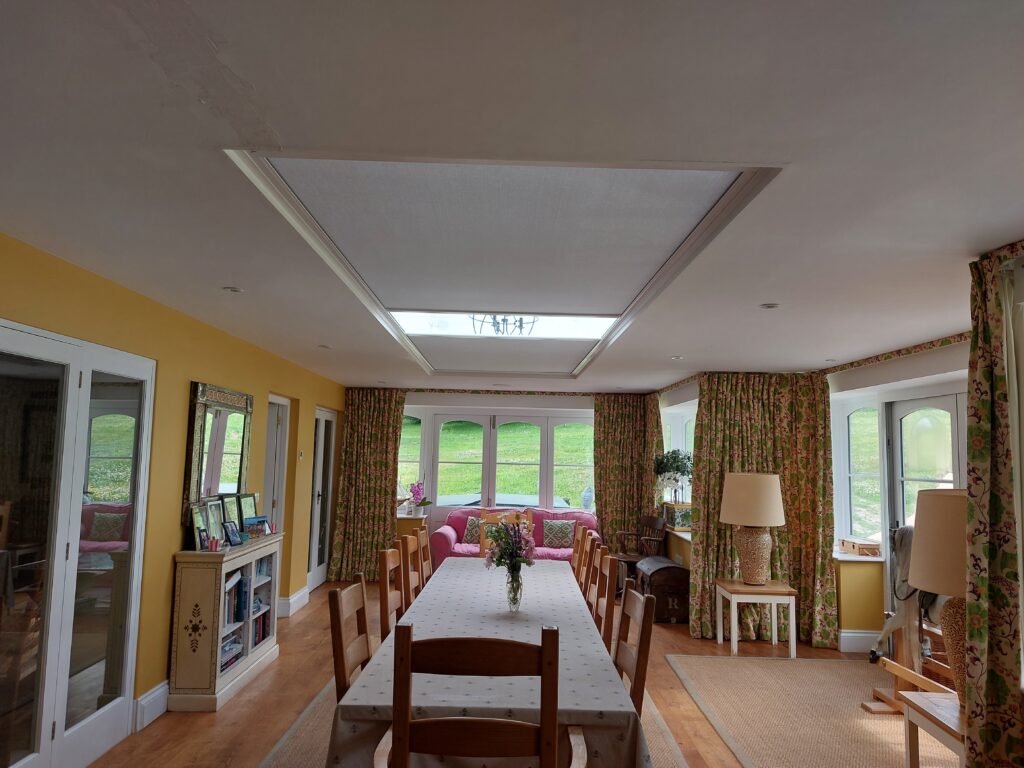 Country dining room with large roof lantern above table, fitted with Twin Athena roof blinds.