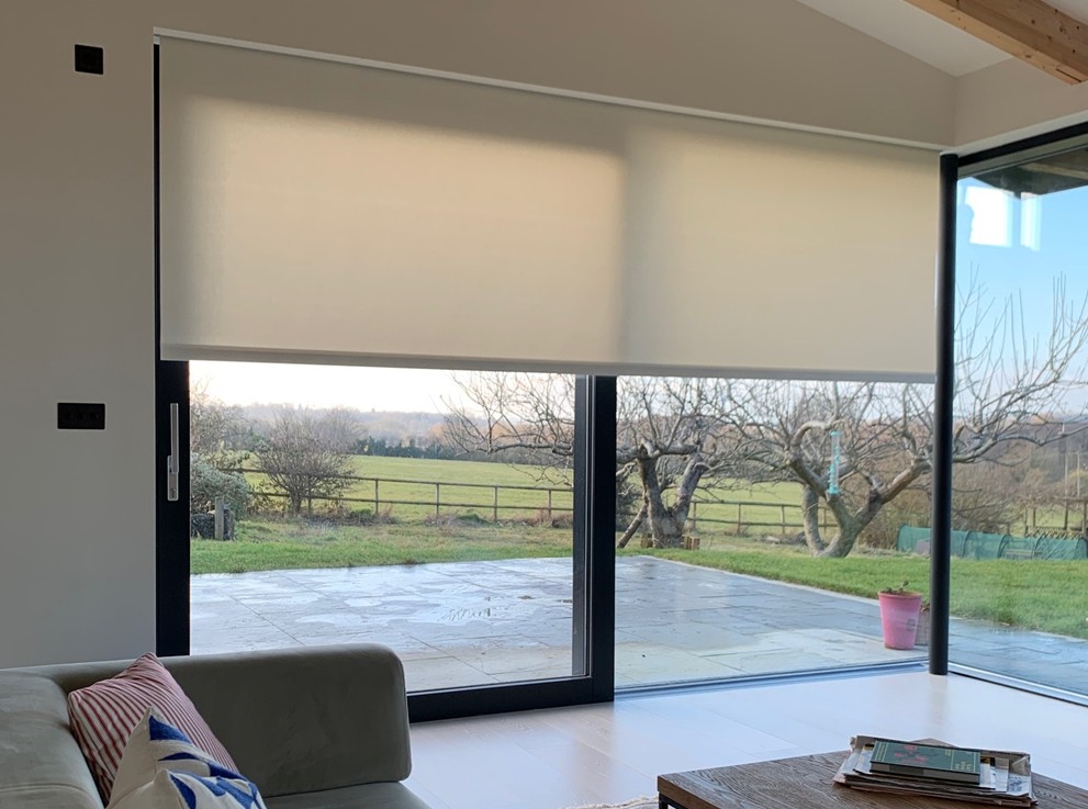 Modern living room with large corner sliding doors and concealed blinds, offering expansive views and natural light.