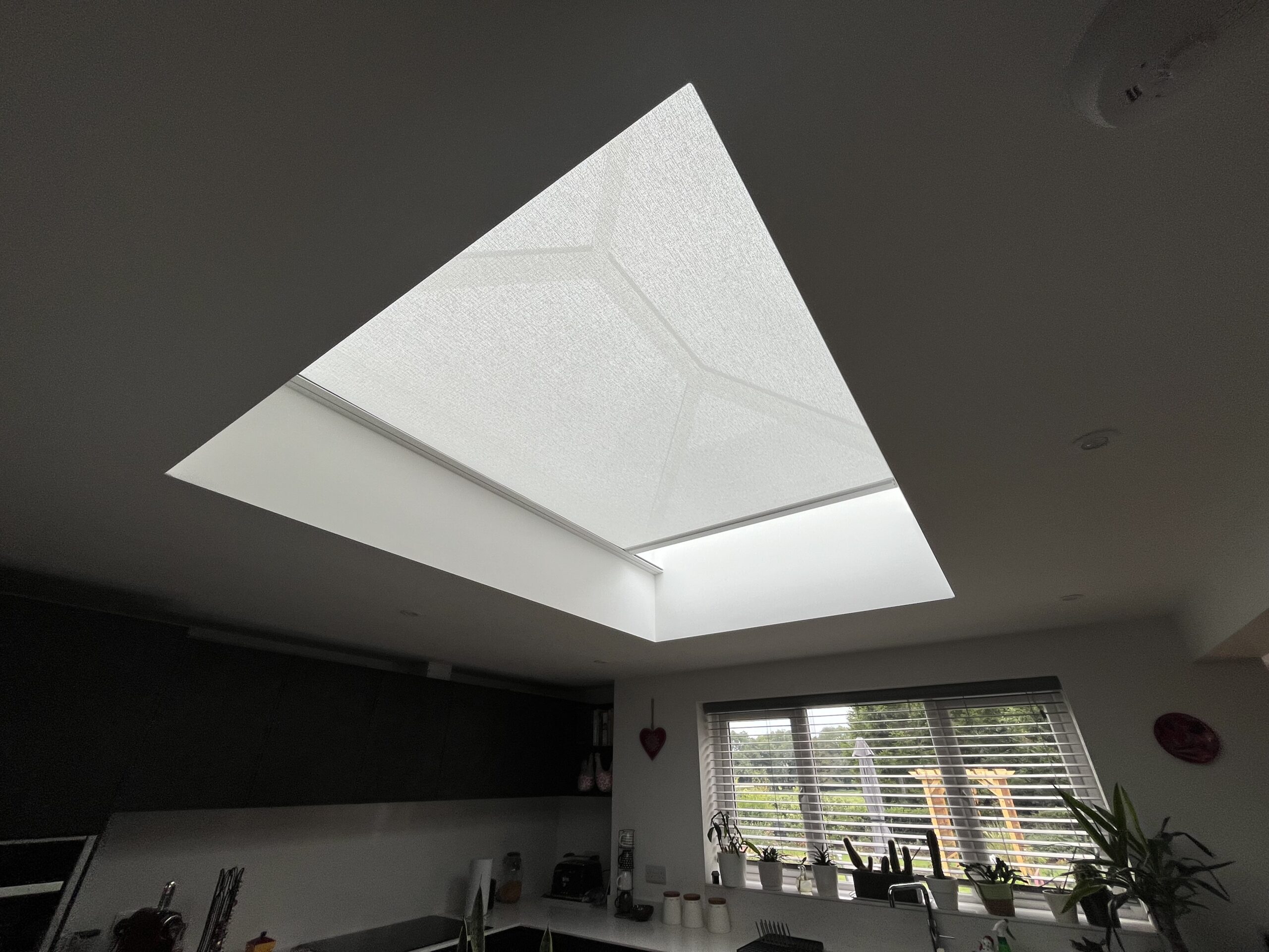 Flat white electric blind retrofitted into a rectangular roof lantern in a modern extension