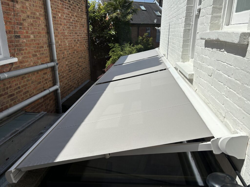 "Three modern awnings shading a glazed side extension, providing stylish sun protection