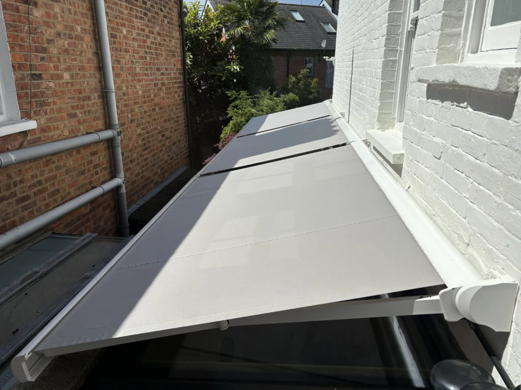 "Three modern awnings shading a glazed side extension, providing stylish sun protection