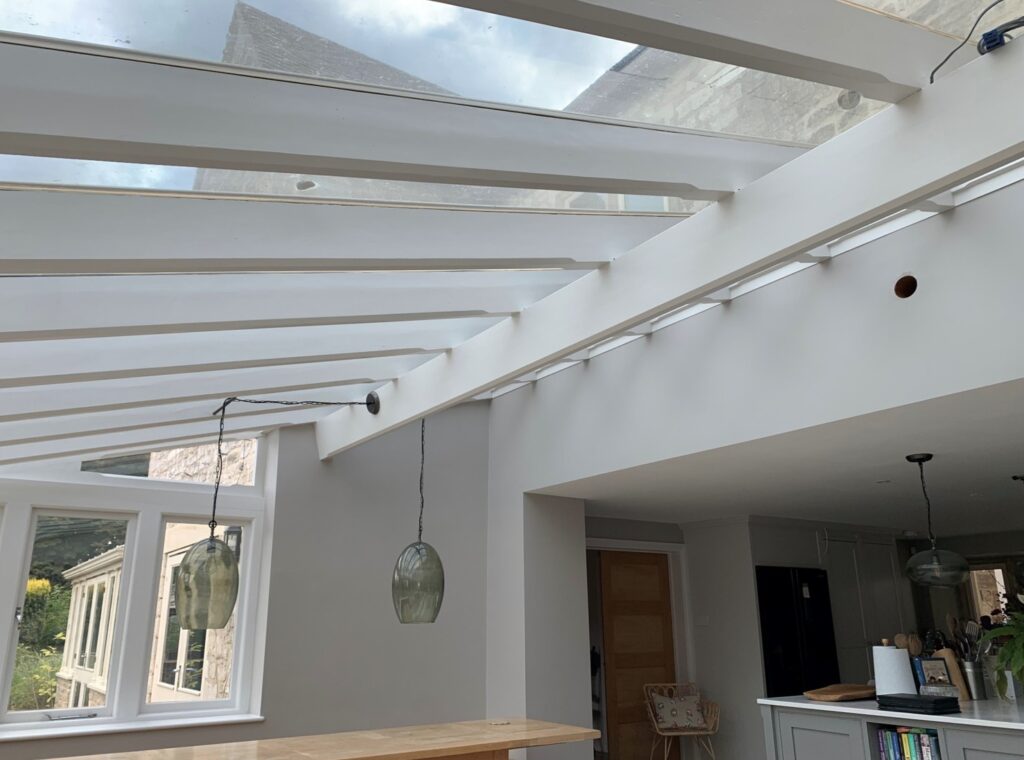 Modern ceiling with white beams and glass roof panels treated with solar control film.