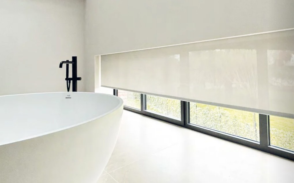 Modern bathroom with a wide roller blind covering horizontal windows, enabled by ZoomTech engineering from Betamech.