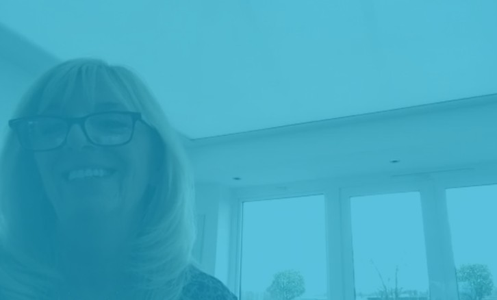 Claire smiling in her bright orangery beneath her Hercules roof lantern blind, with soft daylight filtering through the perfectly tensioned fabric above.