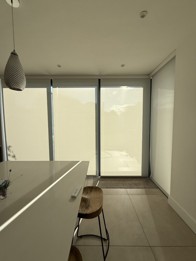 Electric blinds lowering across the bifold doors and return glazing in Caroline and Mike’s extension, diffusing bright sunlight while keeping the space light and comfortable.