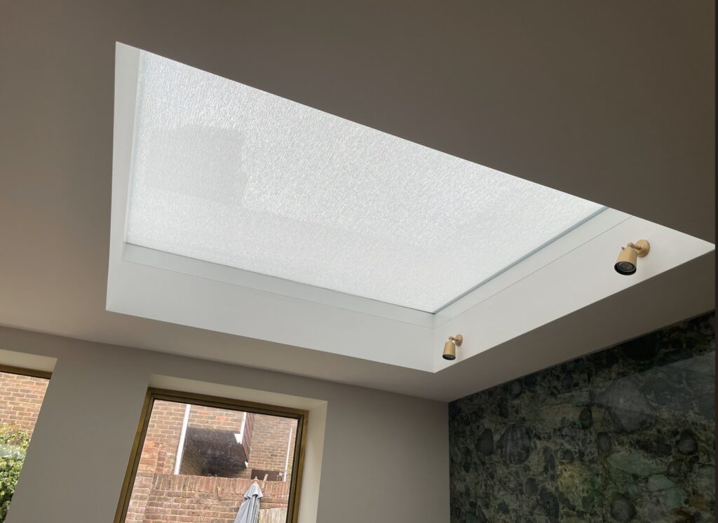 A large skylight with the roof blind fully closed, showing the flat white fabric stretched across the opening.