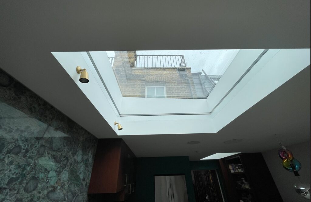 A large skylight viewed from below with the Blindspace roof blind fully retracted and hidden from sight.